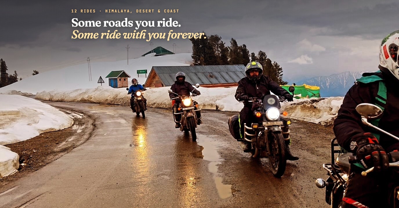 Four motorcyclists riding a wet mountain road lined with snowbanks, with pine forest and snowy peaks behind